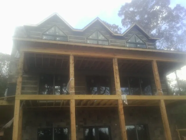 Dormers and porch framing on a large log home under construction — Roof Coating work by our crew in Wesson